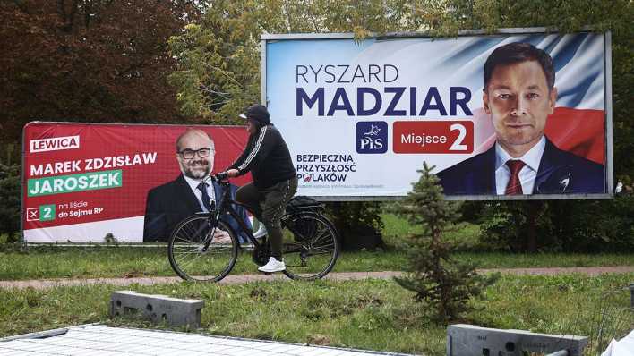 Ein Mann fährt mit dem Fahrrad im polnischen Chelm an Wahlplakaten vorbei.
