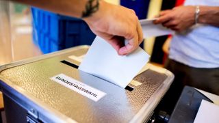 Ein Wähler wirft in einem Wahllokal seinen Stimmzettel für die Bundestagswahl in eine Wahlurne.