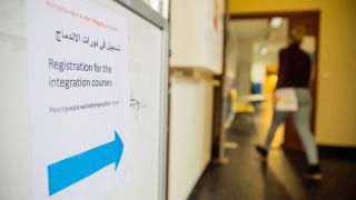Ein Hinweisschild zur Anmeldung zu Integrationskursen steht im Treppenhaus vor dem Eingang einer Berliner Sprachschule