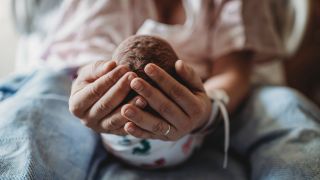 Mutter hält ihr neugeborenes Baby in den Händen