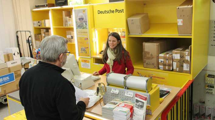 Kunde und Mitarbeiterin einer Deutschen Post Partnerfiliale