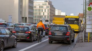 Stau auf der Leipziger Strasse in Berlin. Ein Fahrradfahrer wird von einem verkehrswidrig fahrenden Auto behindert.