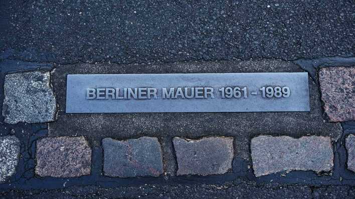 "Berliner Mauer" steht auf der im Boden eingelassenen Platte, die umgeben ist von einem Steinstreifen. Er markiert im gesamten Stadtgebiet den Verlauf der Berliner Mauer.