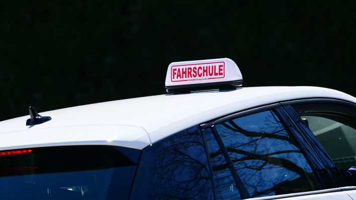 Ein Schild mit der Aufschrift "Fahrschule" ist auf dem Dach eines Fahrschulautos angebracht.