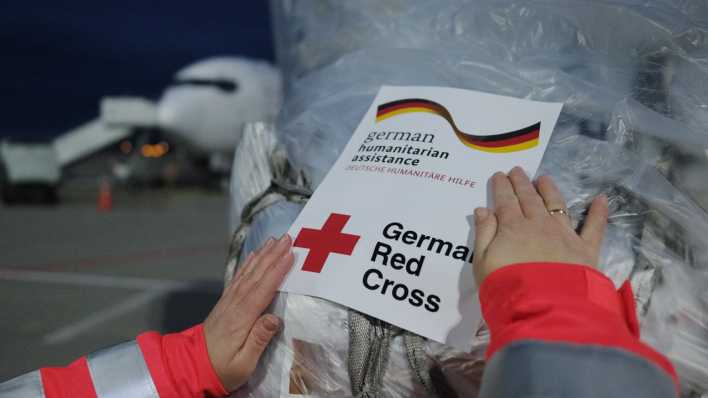 Hilfsgüter werden auf dem Flughafen Leipzig-Halle mit einem Aufkleber des Deutschen Rotes Kreuzes markiert.