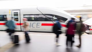 Reisende stehen auf dem Bahnsteig im Hauptbahnhof Hannover, während ein ICE einfährt (Bild: Julian Stratenschulte/dpa)
