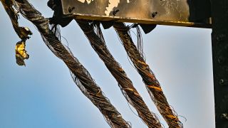 Verbrannte Kabel hängen an einem Strommast auf einem Feld nahe der Tesla-Autofabrik (Bild: picture alliance/dpa/Patrick Pleul)
