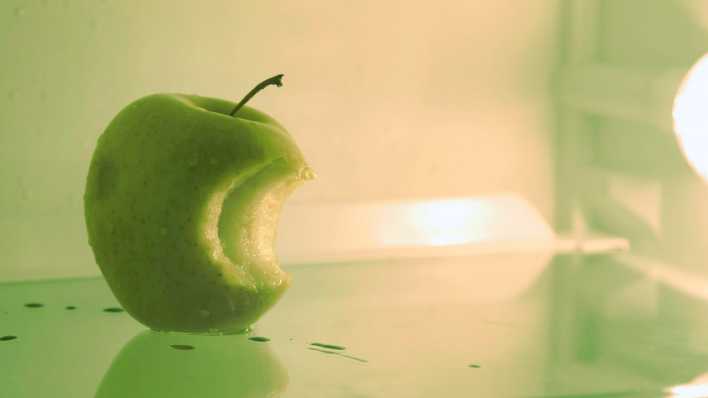 Angebissener grüner Apfel in einem ansonsten leeren Kühlschrank