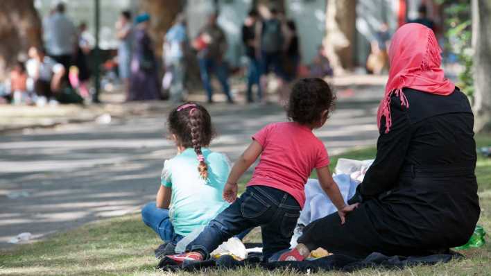 Eine Flüchtlingsfrau und ihre Kinder sitzen in Berlin auf dem Gelände des Landesamtes für Gesundheit und Soziales (Lageso) auf einem Grünstreifen. (Quelle: dpa/Paul Zinken)