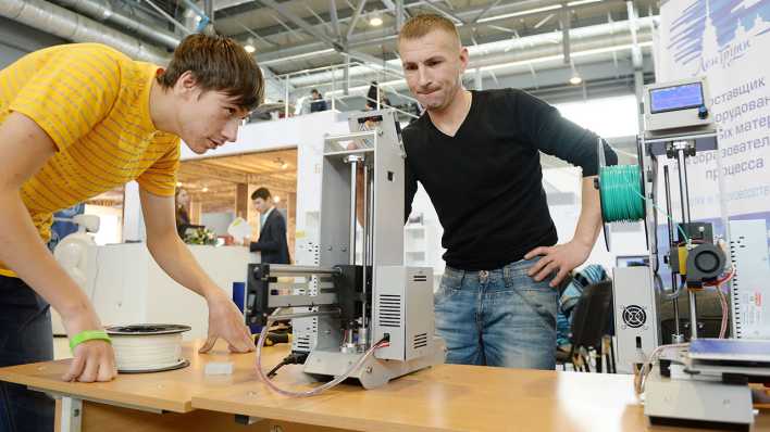 Zwei Männer arbeiten an einem 3D-Drucker (Bild: imago/ITAR-TASS)