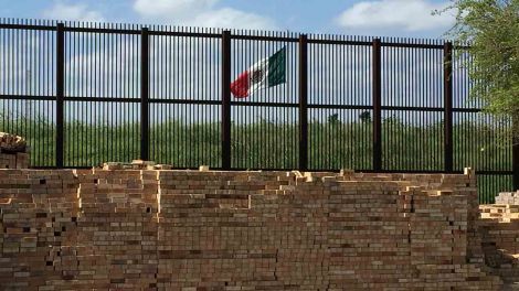 Zaun an der US-Mexikanischen Grenze mit Backsteinen, im Hintergrund die mexikanische Flagge. Quelle: ARD/Andreas Horchler