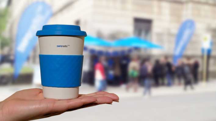 Der Inforadio-Mehrwegbecher steht auf einer Hand