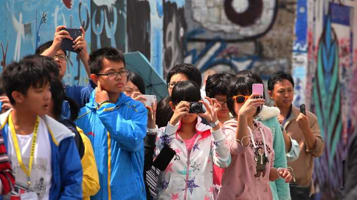 Junge asiatische Touristen machen vor der East Side Gallery in Berlin-Friedrichshain Fotos. (Bild: dpa/Steinberg) Junge asiatische Touristen machen vor der East Side Gallery in Berlin-Friedrichshain Fotos. (Bild: dpa/Steinberg)