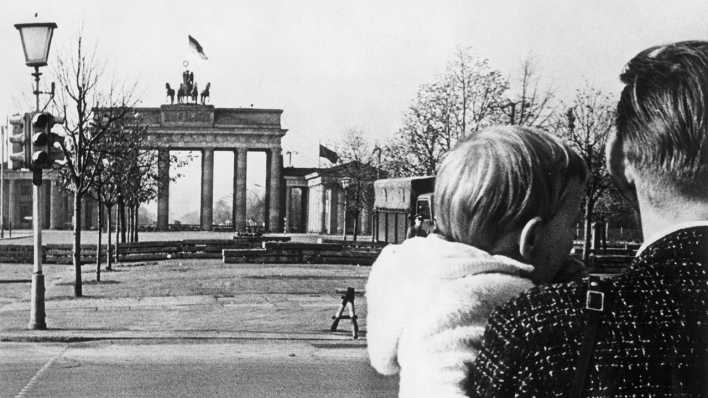 1961: Ein Vater und ein Kind blicken vom Ostsektor auf den Bau der Mauer am Brandenburger Tor. (Bild: akg-images)