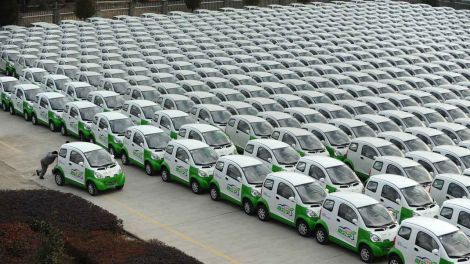 Archiv: Ein Arbeiter schiebt in China eine Elektroauto über einen Parkplatz, auf dem identische Elektroautos stehen. (Bild. imago)