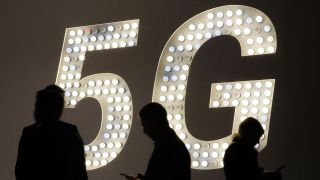 Spanien, Barcelona: Besucher der Technikmesse Mobile World Congress gehen an einer Leuchttafel mit Werbung für den Mobilfunk-Standard 5G vorbei. (Bild: dpa/ Clara Margais)