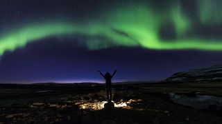 Junge Frau streckt Arme in die Luft, Sternenhimmel mit Nordlichtern (Bild: imago/imagebroker)