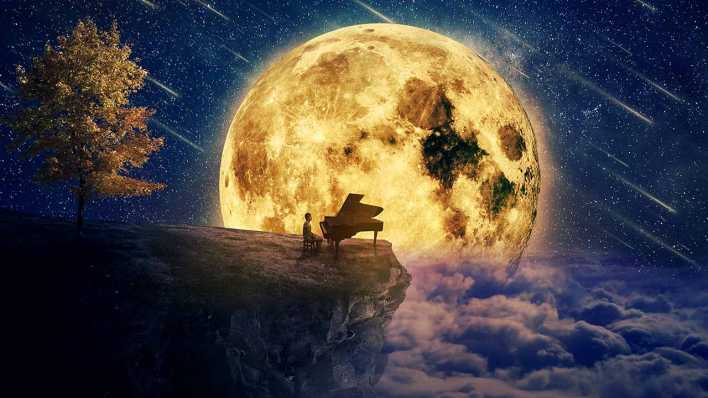 Eine Junge mit Klavier sitzt an einer Klippe vor einem riesigen Mond im Hintergrund (Bild: Colourbox)