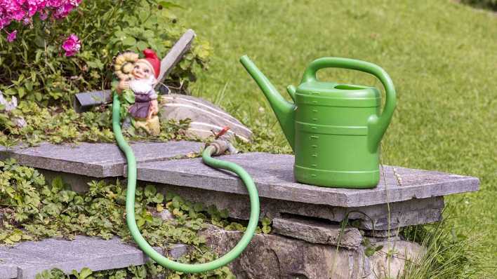 Eine Gißekanne und ein Gartenzwerg in einem Kleingarten (Bild: imago images/CHROMORANGE)