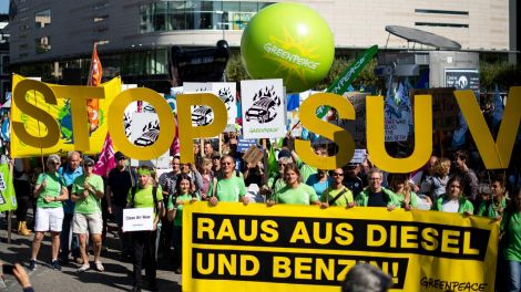 Demonstranten von Greenpeace stehen mit einem Transparent mit der Aufschrift «Raus aus Diesel und Benzin» (Bild: dpa)