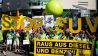 Demonstranten von Greenpeace stehen mit einem Transparent mit der Aufschrift «Raus aus Diesel und Benzin» (Bild: dpa)