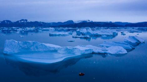 Ein kleines Boot schwimmt inmitten eines Eisbergfeldes bei Grönland (Bild: dpa)