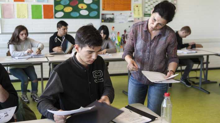 Symboldbild: Eine Lehrerin erklärt einem ihrer Schüler die Aufgaben. Symboldbild: Eine Lehrerin erklärt einem ihrer Schüler die Aufgaben.