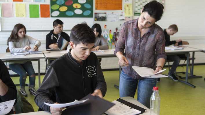 Symboldbild: Eine Lehrerin erklärt einem ihrer Schüler die Aufgaben.