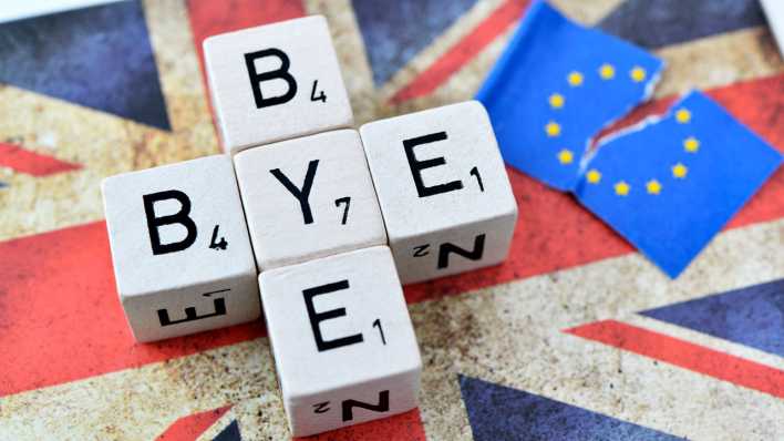 Symbolbild Brexit: Würfelbuchstaben formen den Schriftzug Bye-bye auf der Fahne von Großbritannien neben einer zerrissenen EU-Fahne (Bild: imago images/Christian Ohde)