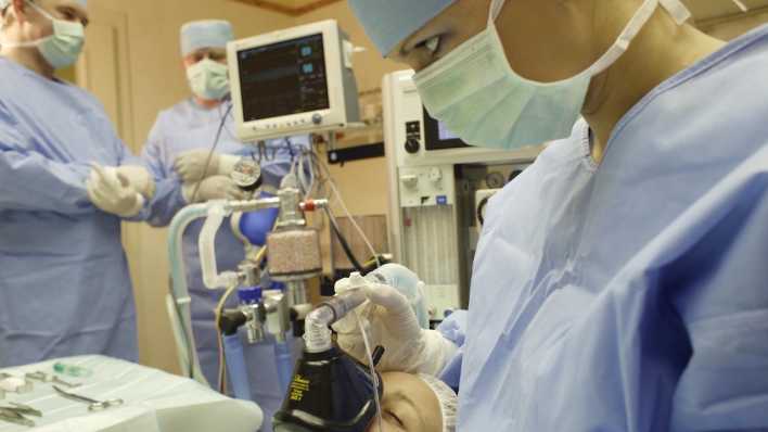 ÄrztInnen und eine Patientin in einem OP-Saal ÄrztInnen und eine Patientin in einem OP-Saal