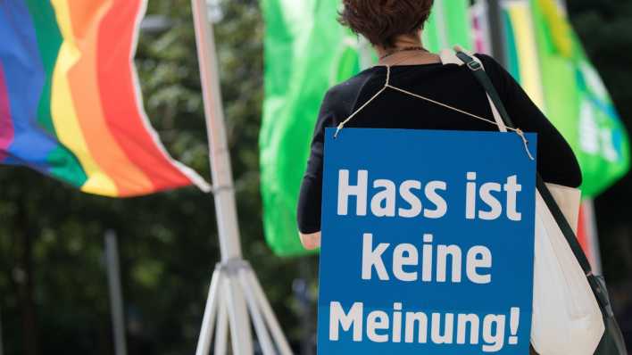 Ein Aktivistin trägt ein Schild mit der Aufschrift "Hass ist keine Meinung" auf dem Rücken