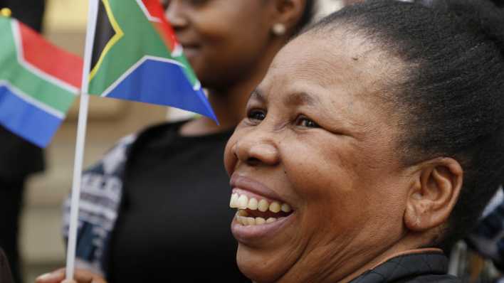 Eine Frau hält eine südafrikanische Flagge hoch.