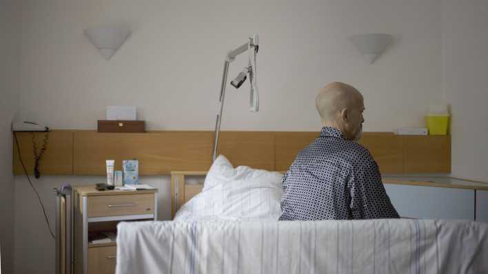 Ein 61-jaehriger Krebspatient sitzt im Palliativzentrum der Uniklinik Koeln auf seinem Bett