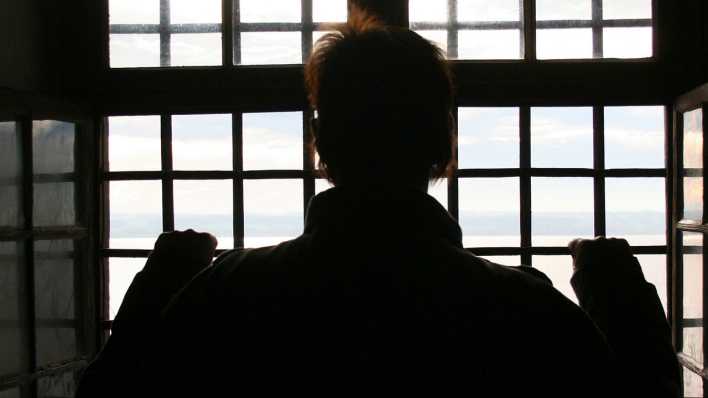 Häftling steht am Gitter seines Zellenfensters