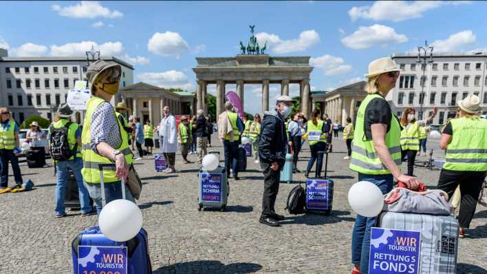Demonstranten stehen mit Abstand zueinander und teilweise mit Mund-Nase-Schutz vor der Brandenburger Tor in Berlin (Bild: imago images / snapshot)