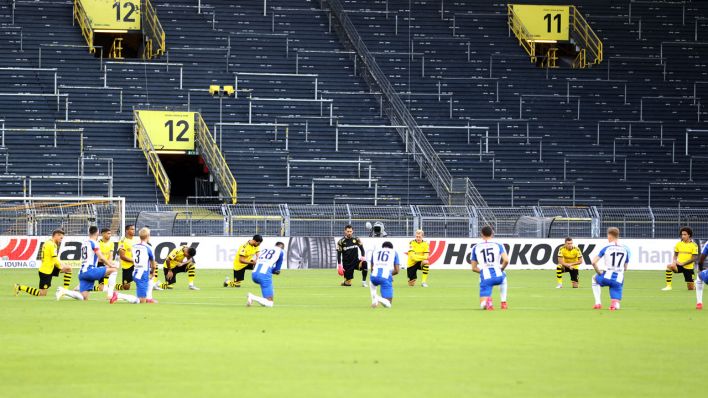 Spieler von Borussia Dortmund und Hertha BSC knien vor dem Anpfiff.