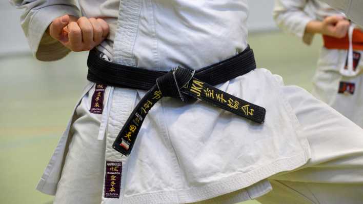 Der schwarzer Guertel eines Karatemeisters ist verziert mit japanischen Schriftzeichen und der Abkürzung des Weltverbands JKA.