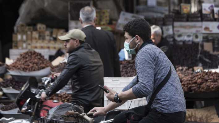 Ein Fahrradfahrer in Syrien fährt mit Mund-Nasenschutz durch die Straßen.