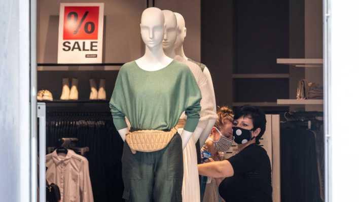 Ein Kleidungsgeschäft in Potsdam: Eine Verkäuferin mit Mund-Nasen-Schutz richtet die Ware im Geschäft.