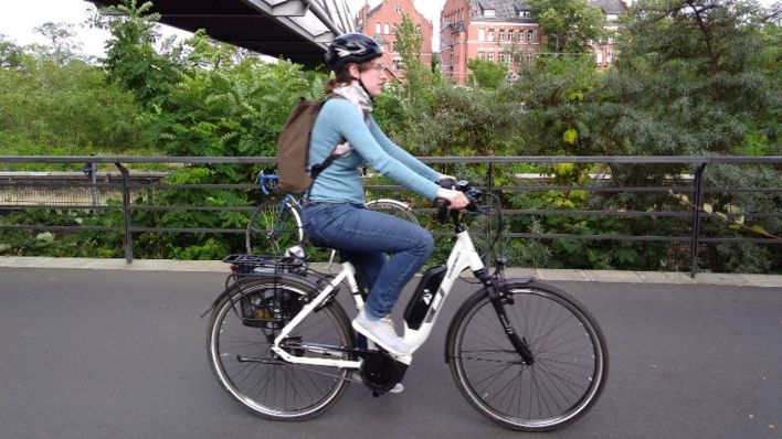 Eine Frau fährt entlang der Berliner Gleise unter einer Brücke.