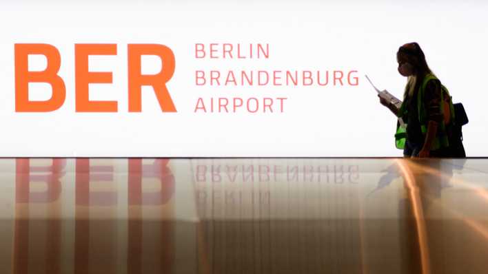 Eine Komparsin in grüner Warnweste geht beim Probelauf im Terminal 1 des Hauptstadtflughafens Berlin-Brandenburg (BER) zum Gepäckband (Bild: dpa)