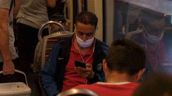 Mann in der U-Bahn mit falsch sitzendem Mund-Nase-Schutz