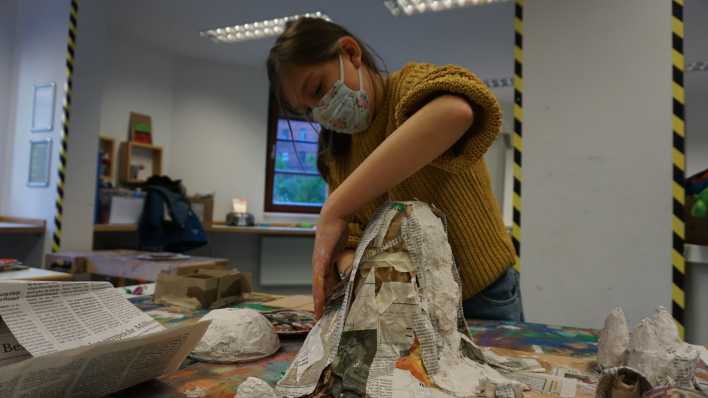 Ein Mädchen bastelt eine Figur aus Pappmaché