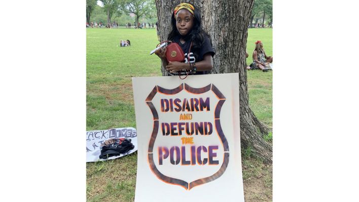 Teilnehmerin des March on Washington mit Protestplakat "DISARM AND DEFUND THE POLICE"