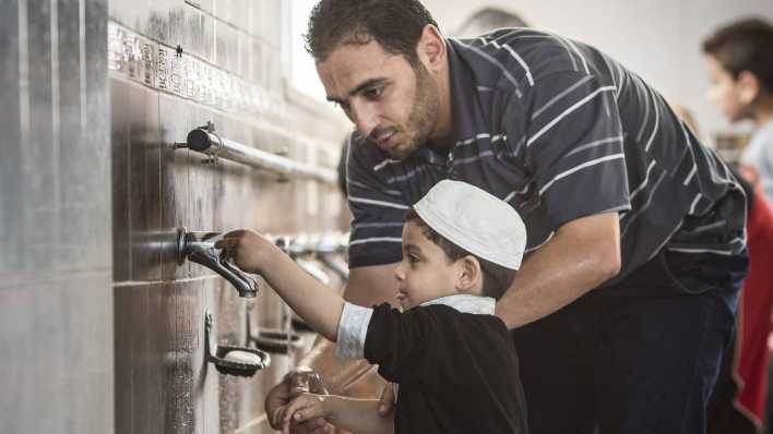 Muslimischer Vater und sein kleiner Sohn bei der rituellen Waschung vor dem Gebet in einer Moschee