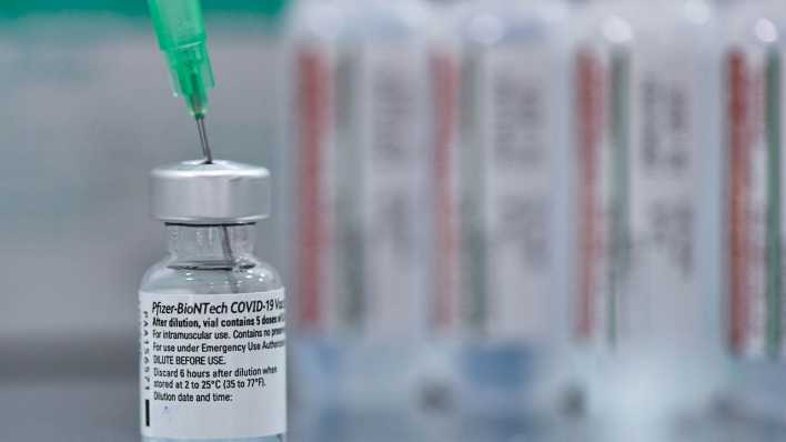 Im Impfzentrum Cottbus steht eine kleine Ampulle mit einer Kanüle für die Impfung gegen Covid-19 mit dem Impfstoff von Biontech/Pfizer.