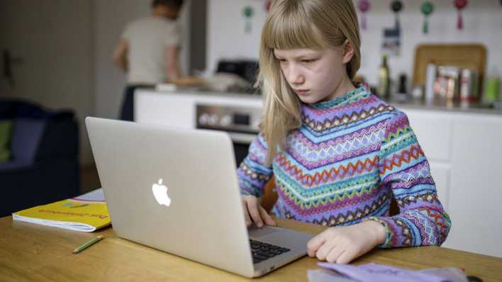 Eine Berliner Schülerin sitzt beim Homeschooling in der Küche am Laptop