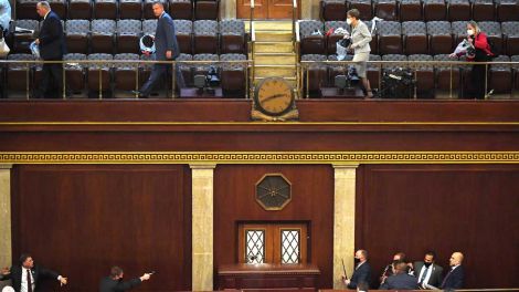 Abgeordnete verlassen das Parlament, während Polizisten mit gezogenen Waffen einen Eingang sichern (Bild: imago images/UPI Photo)