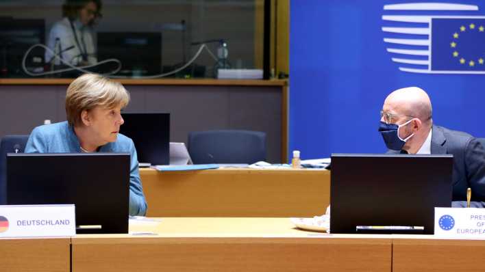 Bundeskanzlerin Merkel und EU-Ratspräsident Michel unterhalten sich am Tisch (Bild: picture alliance / AA)