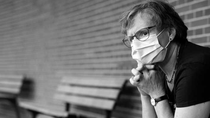 Eine ältere Dame mit Mundschutz sitzt nachdenklich auf einer Bank. (Bild: picture alliance / Eibner-Pressefoto | Weber/ Eibner-Pressefoto)